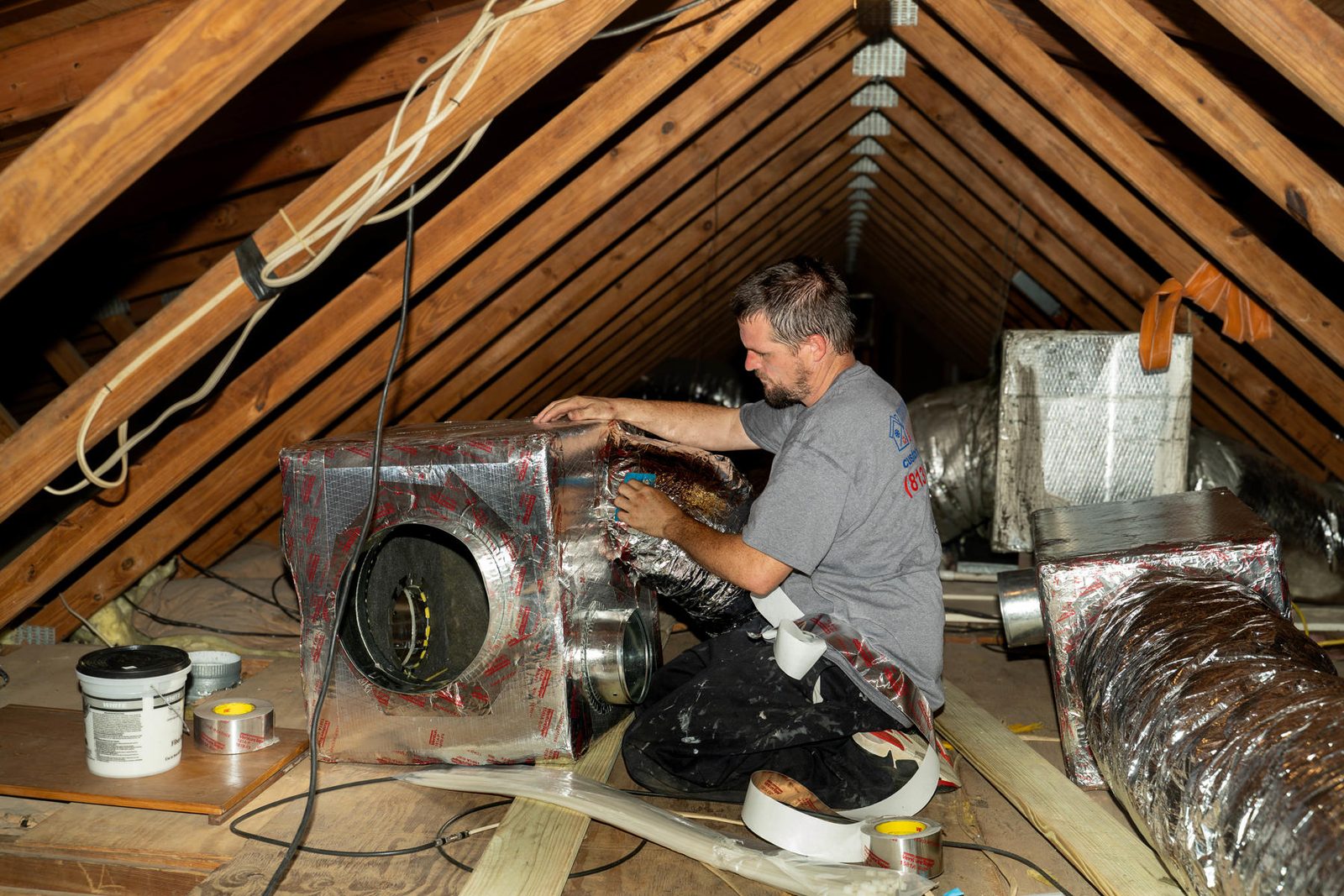 Technician servicing an attic air handler